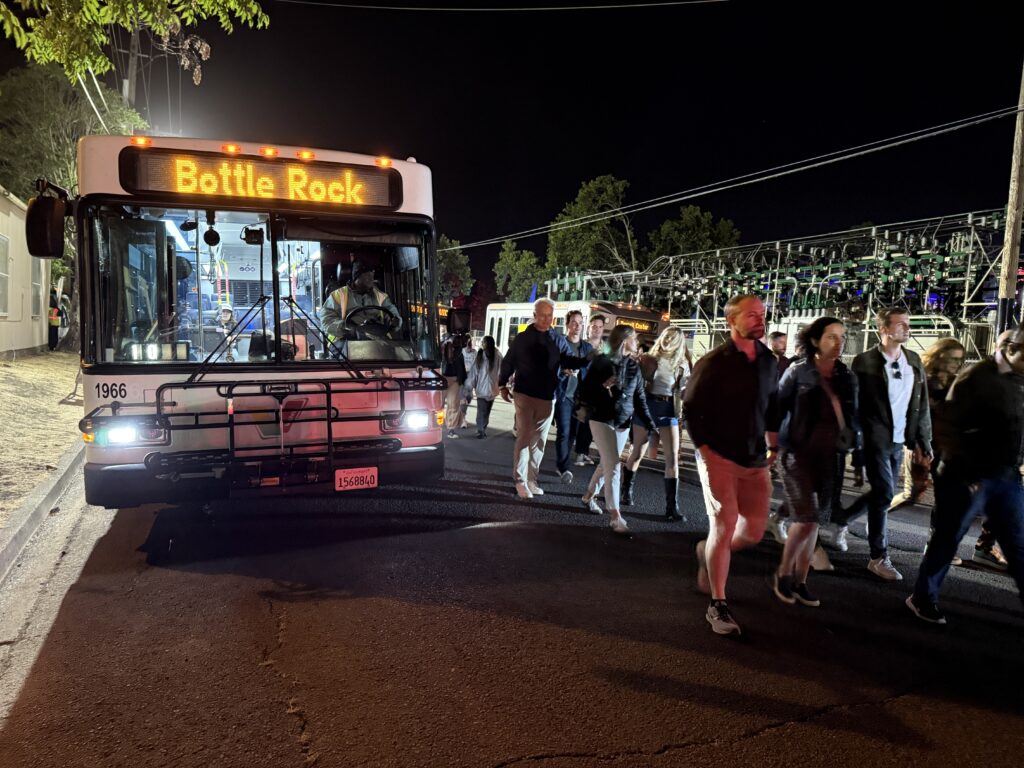 A large crowd of people walk past one of Vine Transit's specialty BottleRock bus, a free service offered all festival weekend.