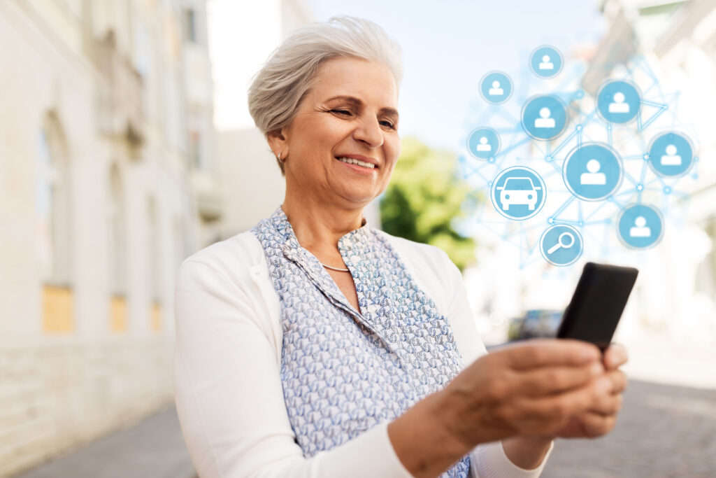 An elderly woman looks at a rideshare app on her phone. 